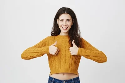 Una mujer sonriendo con los pulgares hacia arriba